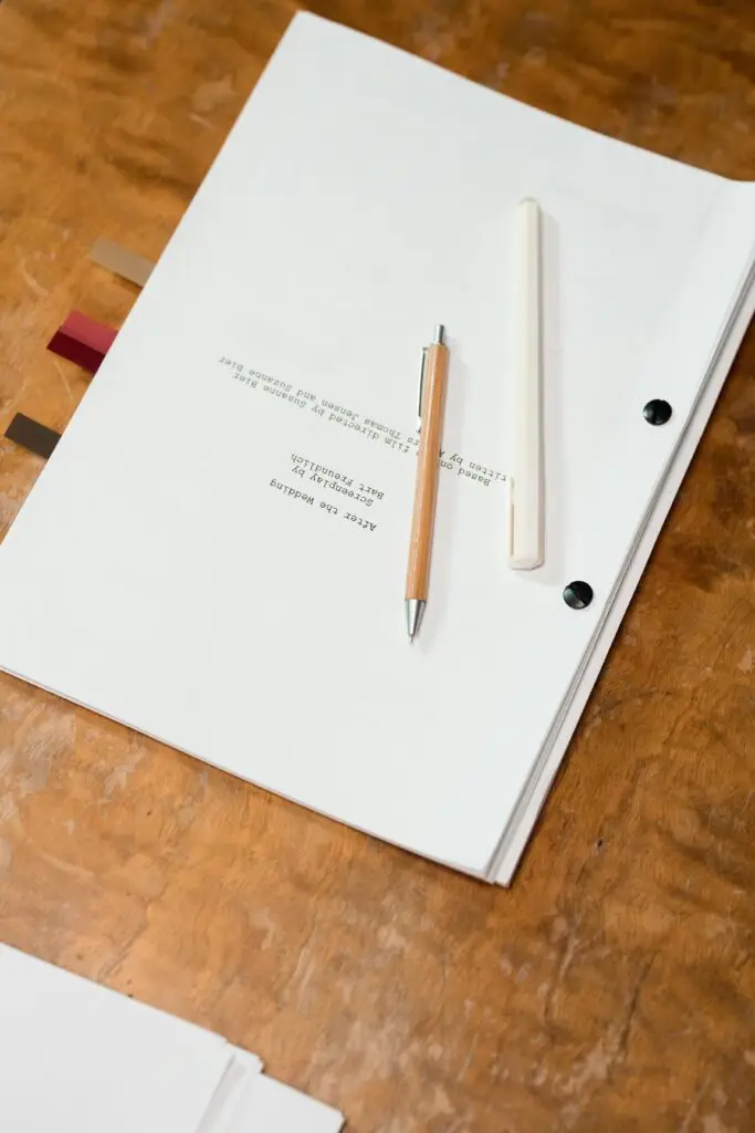 Close-up of papers and pens on a wooden table, perfect for writing and office themes.